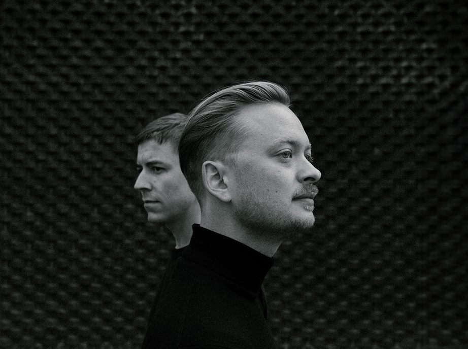 Black and white portrait of Studio 28K founders Jonas Emmertsen and Steffen Christiansen in profile, facing opposite directions against a textured dark wall.