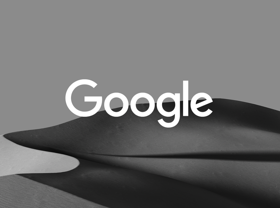 Google logo in white over grey sand dunes in black and white.