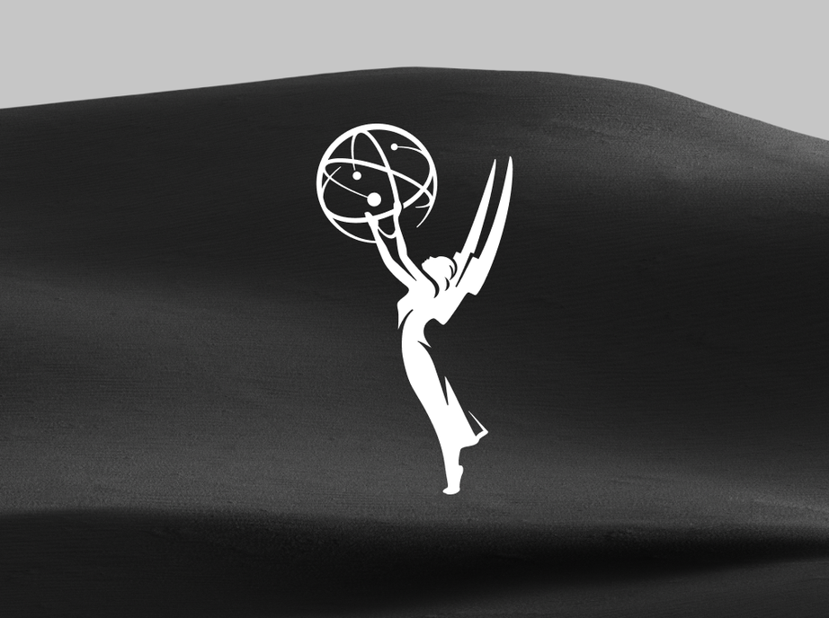 Emmy Awards statuette logo in white over a dark sand dune under a grey sky.