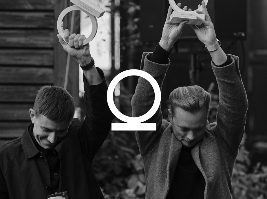 Black and white photo of Studio 28K founders Jonas Emmertsen and Steffen Christiansen raising their Creative Circle trophies above their heads, with the Creative Circle logo overlaid in white.