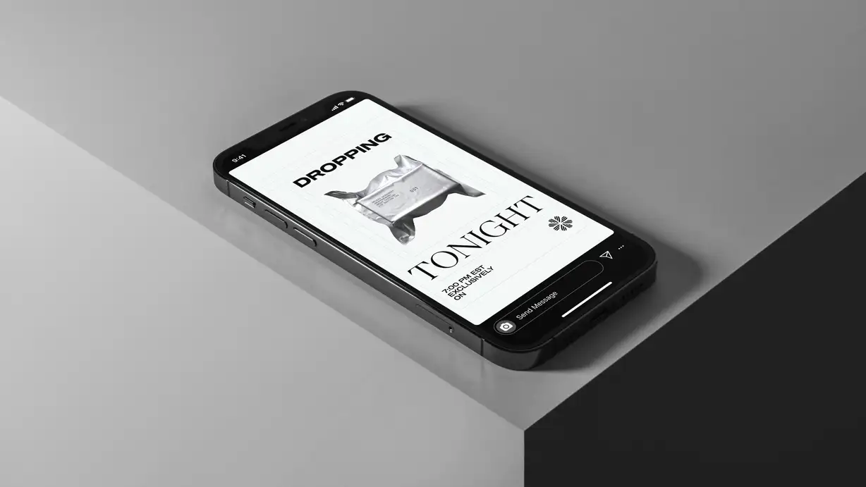 A black smartphone lying on the edge of a light gray surface at an angle, displaying an Everbloom social-media story in portrait orientation. The status bar reads 9:41. The story is set on a white background with bold black text reading "DROPPING" at the top and "TONIGHT" in large serif type lower down, framing a photo of a silver foil-wrapped package or product. Smaller text reads "7:00 PM EST EXCLUSIVELY ON" beside the Everbloom floral logo. An Instagram-style "Send Message" bar with camera, share, and more icons sits at the bottom of the screen.
