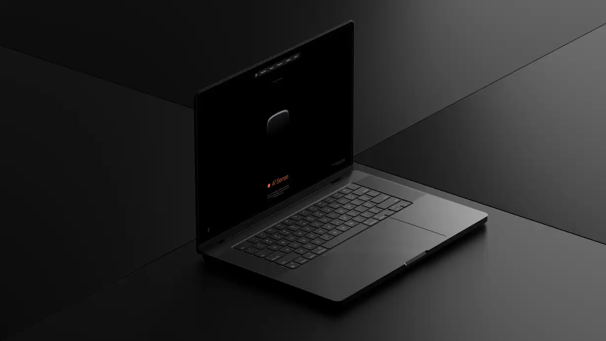 An open laptop photographed at an angle in a dramatically dark, low-lit setting, the machine and its surroundings all in deep black and charcoal tones. The screen displays the Augen "A¹ Sense" product page: a dark navigation bar with the starburst logo and menu links (Wearable, Neural, Programs, Updates, Search) sits at the top, a dimly lit render of the small wearable device floats in the center, and near the bottom the product name "A¹ Sense" appears in orange beside a small orange marker, above faint descriptive text. The laptop's backlit keyboard and trackpad are visible in the foreground.