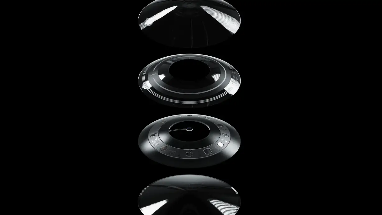 A dramatic exploded-view product render of the Augen B¹ Eye smart contact lens against a pure black background, its layers stacked vertically and separated to show internal construction. The top layer is a smooth, glossy transparent dome (the outer lens surface). The middle layer is a dark ring engraved with the Augen starburst logo and fine circular detailing. The bottom layer reveals the intricate technology embedded in the lens — a ring of miniaturized circuitry, sensors, and components surrounding a central point. A soft reflection of the lowest layer appears on the glossy black surface beneath.