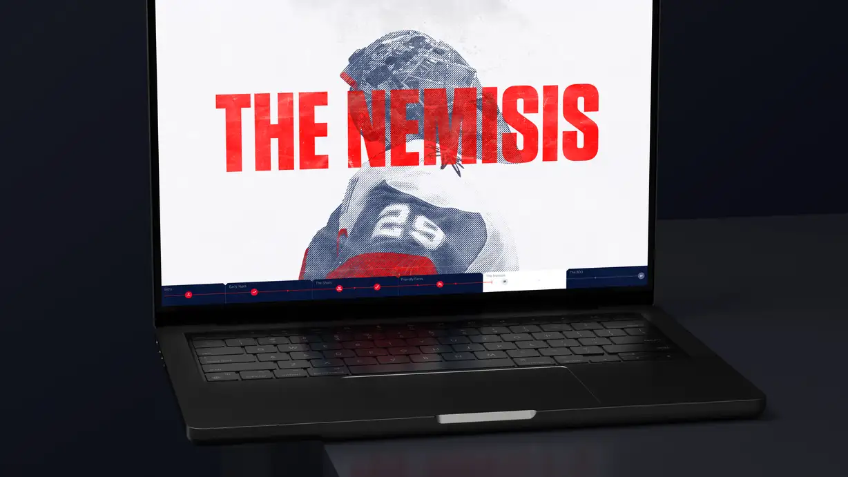An open laptop shown at a dramatic angle on a dark surface, displaying a chapter screen from the "OVECHKIN 800" hockey feature. The screen shows a large, halftone/duotone treated photo of a hockey player (in a red-and-white Capitals jersey, number 8) set against a white background, overlaid with the bold red title "THE NEMISIS." A horizontal chapter-navigation timeline runs across the bottom of the screen with labeled sections: Intro, Early Years, The Shots, Friendly Faces, The Nemisis (currently active), and The 800, each marked with red icons and progress dots. The laptop's dark backlit keyboard and trackpad are visible in the foreground.