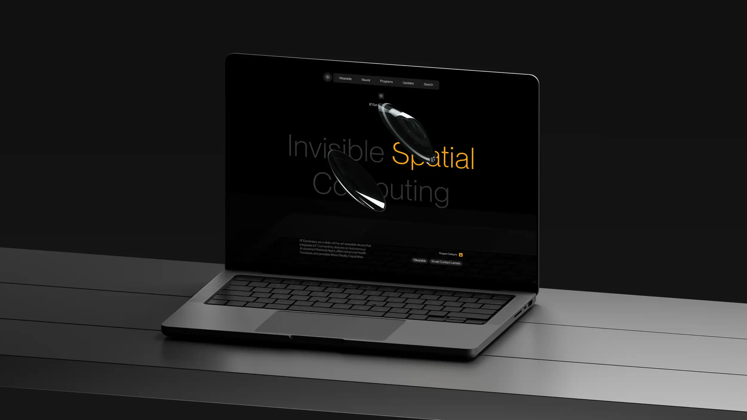 An open laptop photographed at an angle on a dark gray desk in a moody, low-lit setting. The screen displays the Augen "B¹ Eye" product page in near-black with amber-yellow accents: a dark navigation bar at the top (starburst logo; menu links Wearable, Neural, Programs, Updates, Search), the label "B¹ Eye A Pioneer In," and a large display headline reading "Invisible Spatial Computing" (with "Spatial" in yellow) wrapped around two renders of the curved, transparent smart contact lenses. Below, supporting text reads "B¹ Eye lenses are a state-of-the-art wearable device that integrates IoT Connectivity, features an Autonomous AI-powered Personal Agent, offers advanced Health Functions, and provides Mixed Reality Capabilities," accompanied by a "Program Category" label with "Wearable" and "Smart Contact Lenses" tags. The laptop's dark keyboard and trackpad are visible in the foreground.
