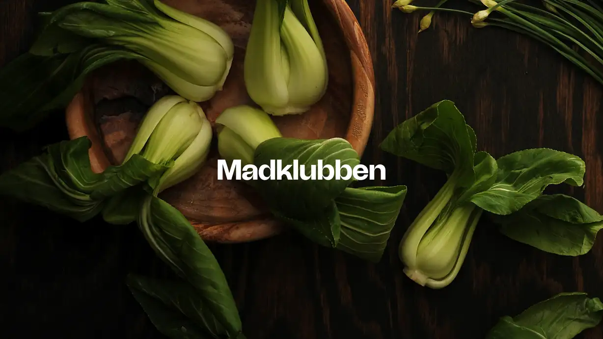 Image of bok choi in a wooding bowl with a logo on top saying 'Madklubben'