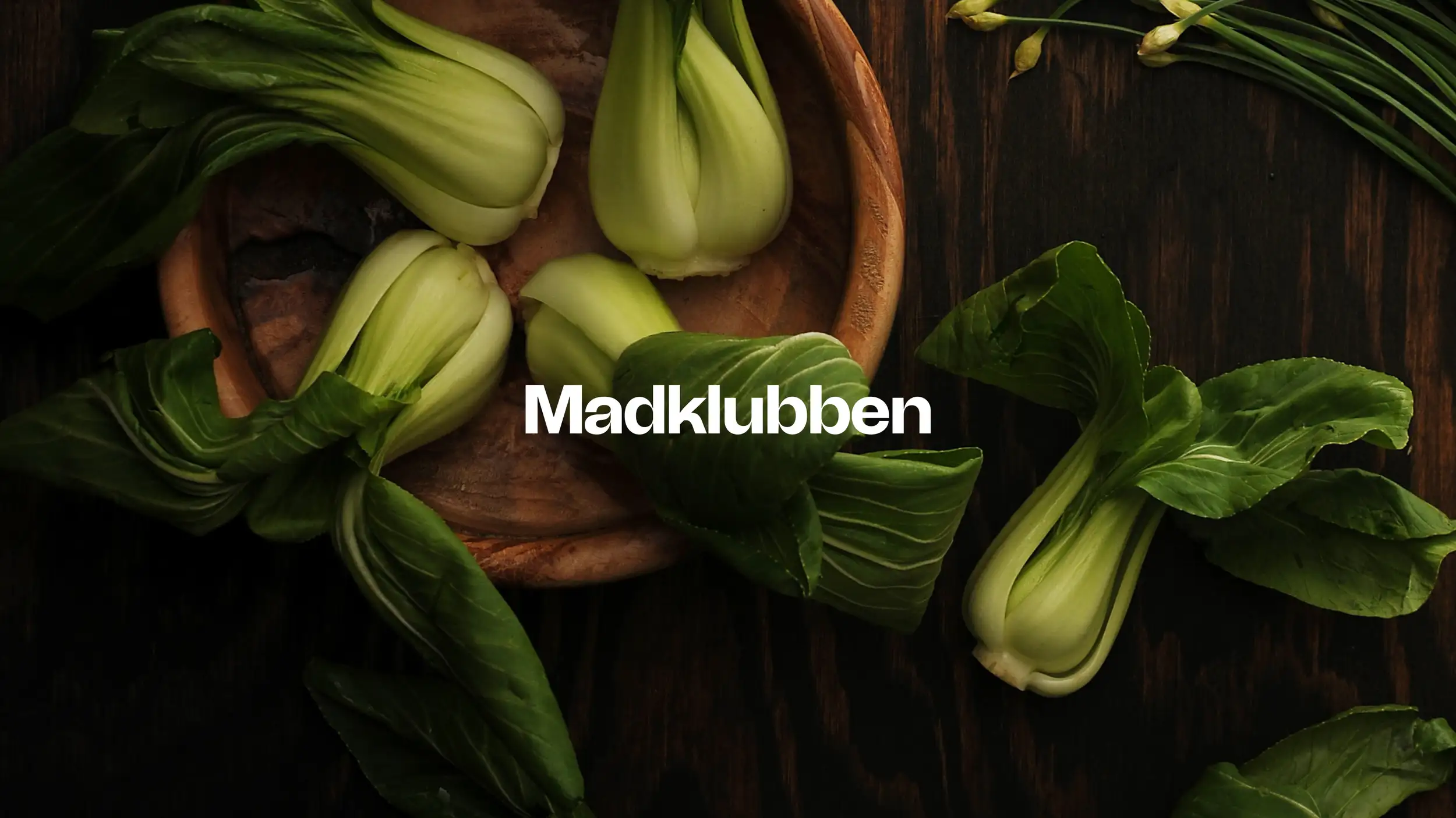Image of bok choi in a wooding bowl with a logo on top saying 'Madklubben'
