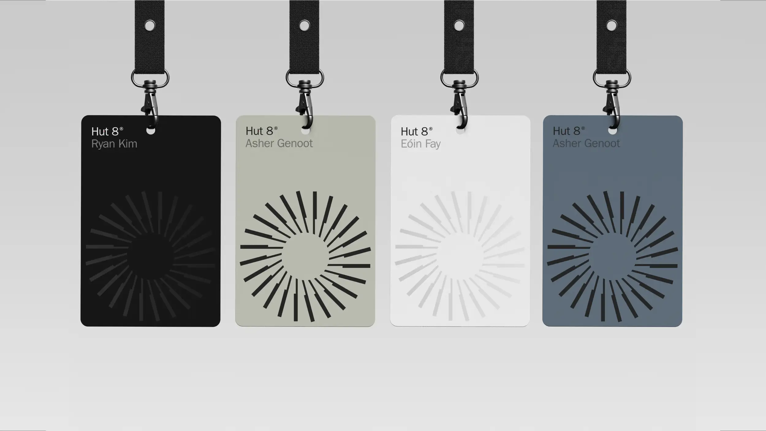 Four Hut 8 ID badges on black lanyards in black, sage green, white, and slate blue, each printed with a name and a circular sunburst logo.