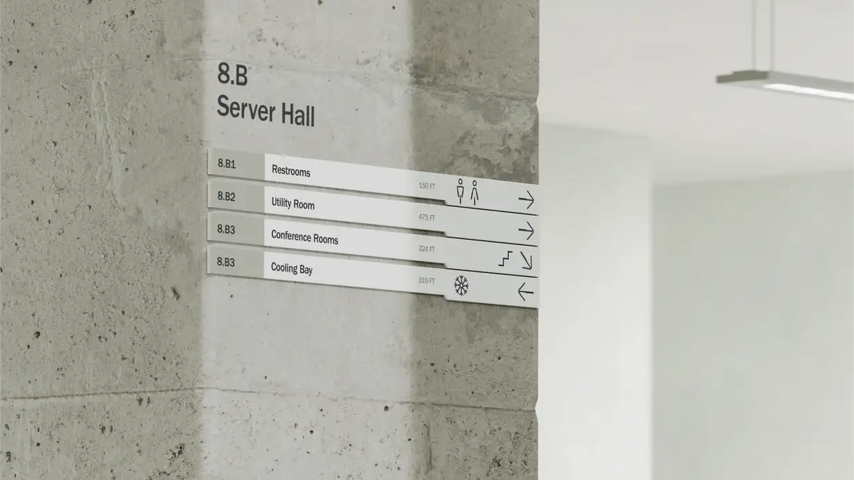 A directional wayfinding sign mounted on an exposed gray concrete pillar in a minimalist industrial interior, with a suspended linear light fixture visible on the blurred white wall to the right. The sign is headed "8.B — Server Hall" in black type. Below are four horizontal directory bars, each with a room code, label, distance, icon, and direction arrow: "8.B1 Restrooms — 150 FT" (restroom figures, arrow right), "8.B2 Utility Room — 475 FT" (arrow right), "8.B3 Conference Rooms — 324 FT" (stairs and down-right arrow), and "8.B3 Cooling Bay — 310 FT" (snowflake icon, arrow left).