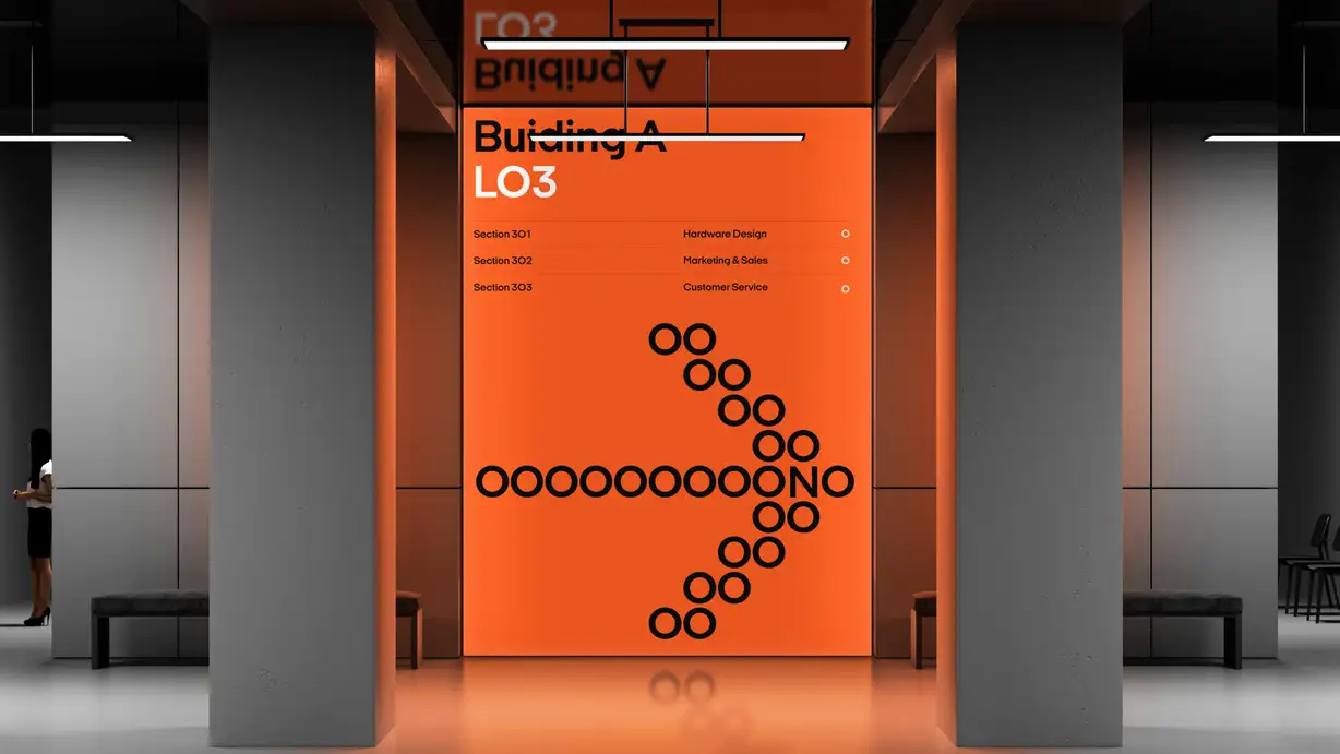 An interior signage render: an illuminated orange panel between two gray pillars reading "Building A, L03" with a directory list (Hardware Design, Marketing & Sales, Customer Service) and a diagonal arrow formed from black circles spelling out "OOONO," with a person walking past at left and a mirrored sign visible above.