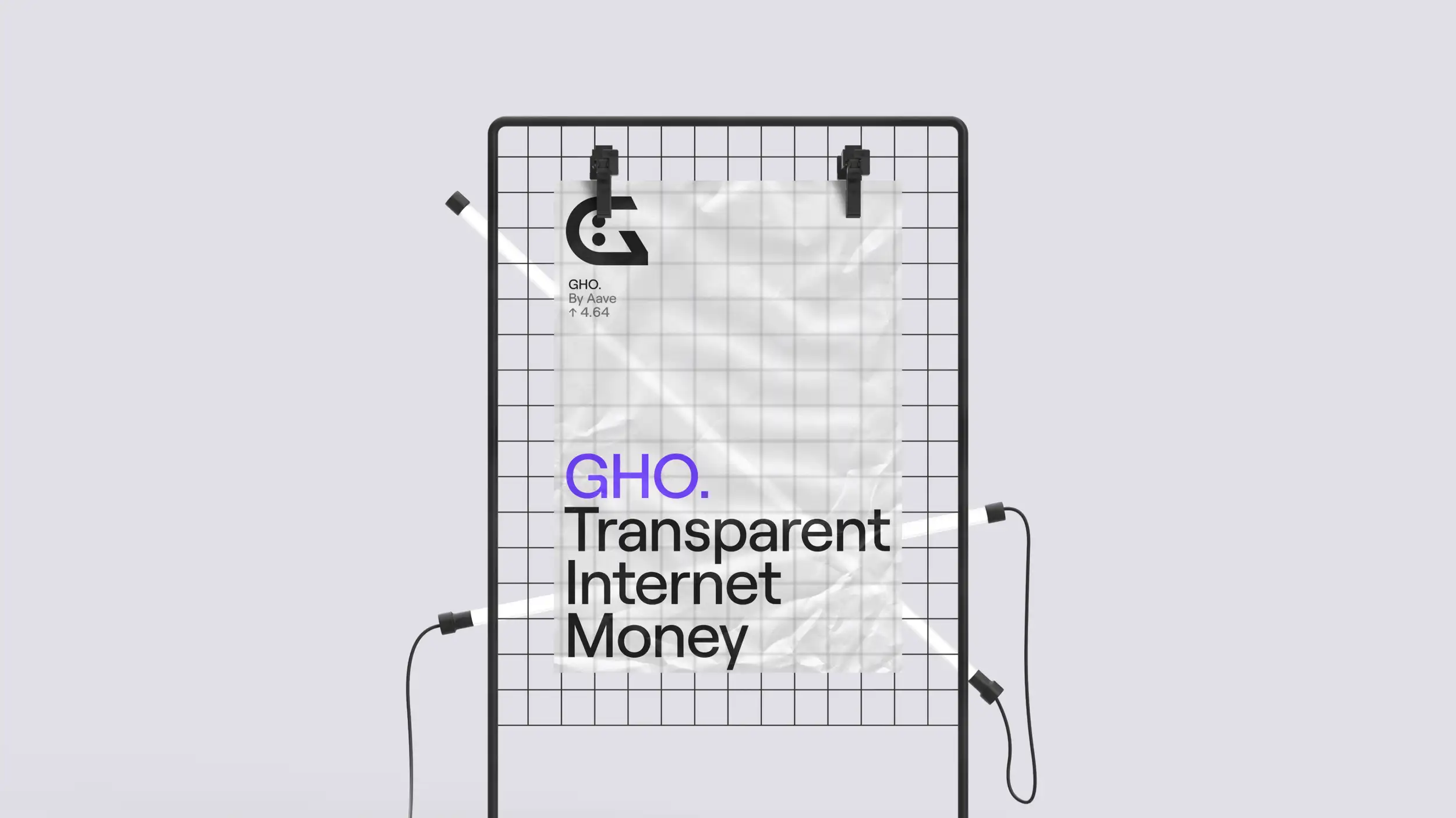 A GHO brand poster clipped to a black metal wire-grid display stand against a light lavender-gray background, with two thin white LED tube lights crossing diagonally in front. The slightly crumpled poster is held by two black clips at the top. Its upper-left corner shows the "G" face logo with "GHO. By Aave ↑ 4.64," and the lower half carries the headline "GHO." (in purple) above "Transparent Internet Money" in large black type.